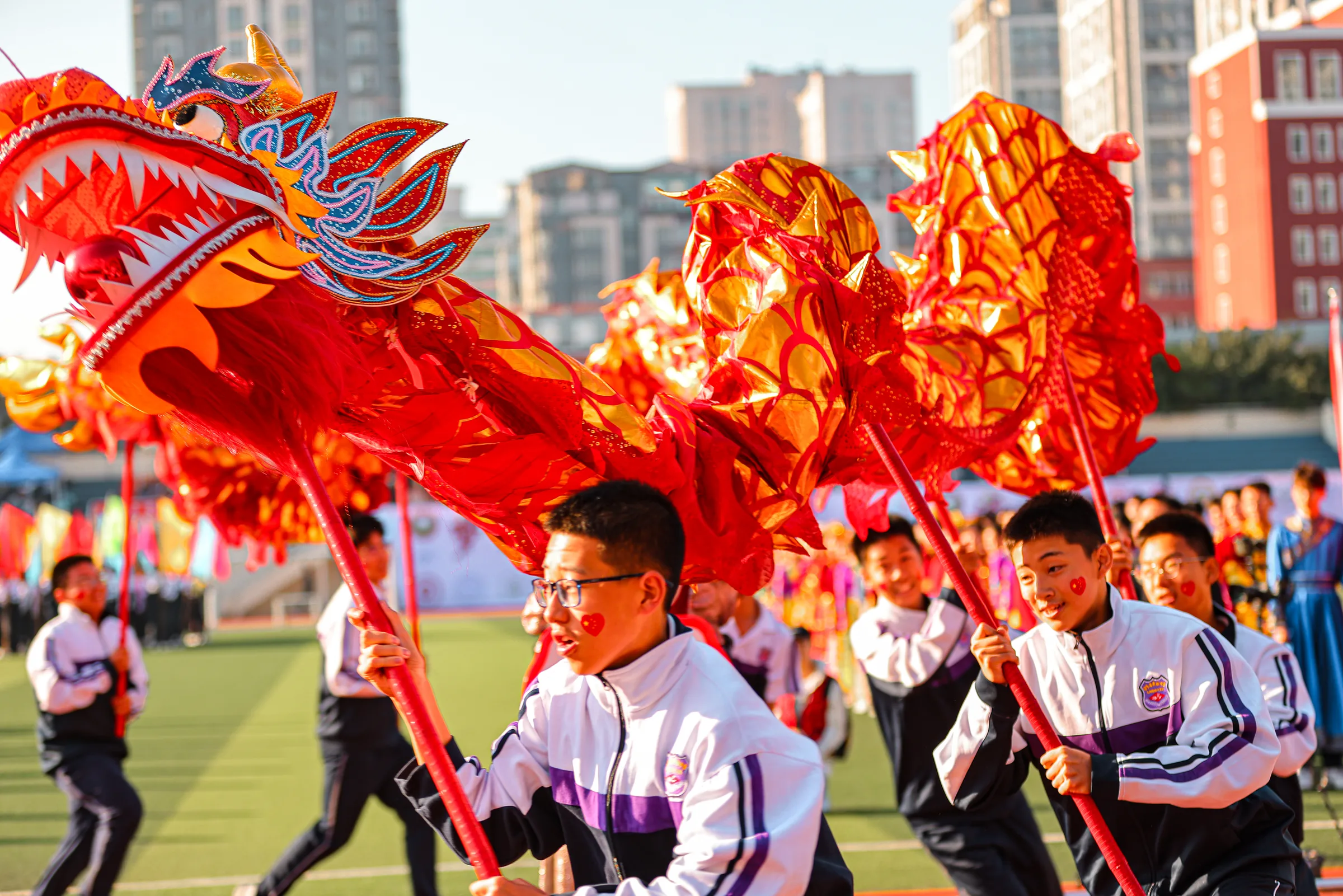 鲜红龙身在阳光下翻腾，学生们在下方配合舞动