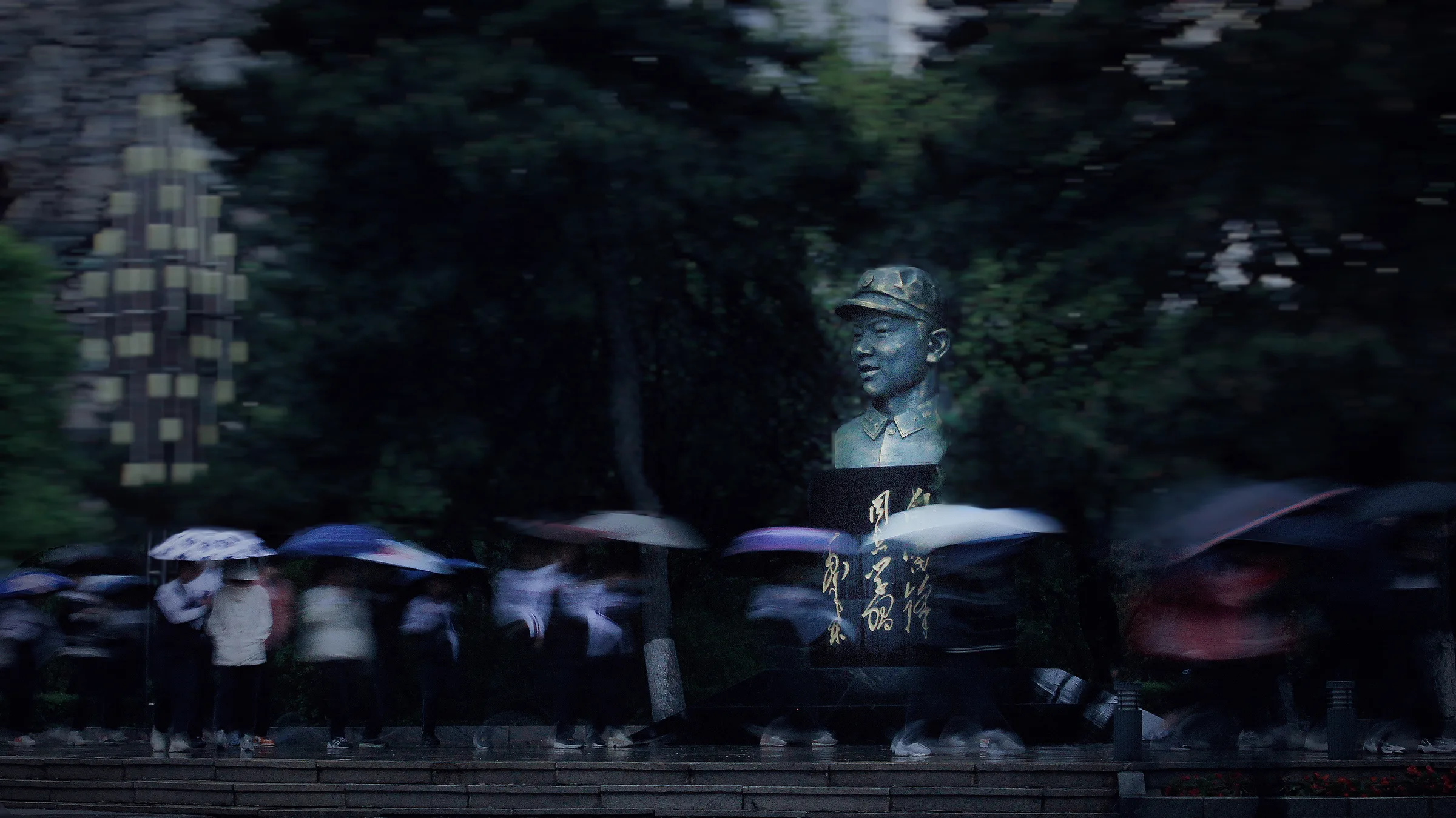 雨中人群撑伞经过铜像前